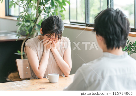 A woman crying in shock at a cafe, eatery or restaurant on a date (sad, couple quarrel) 115754065