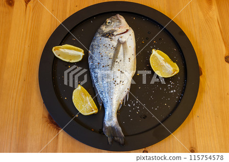 Raw fresh fish dorado with lemon and spices on wooden table. Top view 115754578