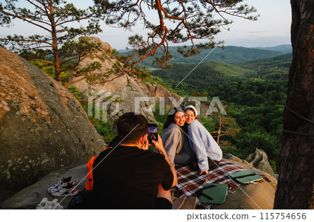 happy friends eating pizza at the cliff with beautiful mountain view 115754656