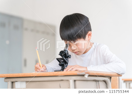 Elementary school boy experimenting and studying science in school class (microscope, looking) Elementary school boy experimenting and studying science in school class (microscope, looking) 115755344