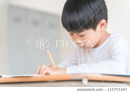 一名小學低年級男孩在學校/補習班的教室裡上課 一名小學低年級男孩在學校/補習班的教室裡上課 115755347