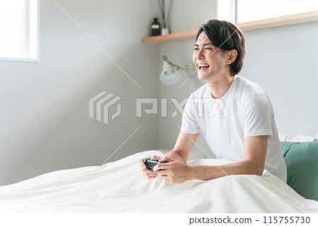 Male gamer playing games in the bedroom at home (inconsistent, playing, stress relief) 115755730