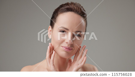 Beauty, health, cosmetics, anti-aging therapy and skin care concept - young beautiful brunette Caucasian woman touching face and looking at camera Beauty, health, cosmetics, anti-aging therapy and skin care concept - young beautiful brunette Caucasian woman touching face and looking at camera 115756028