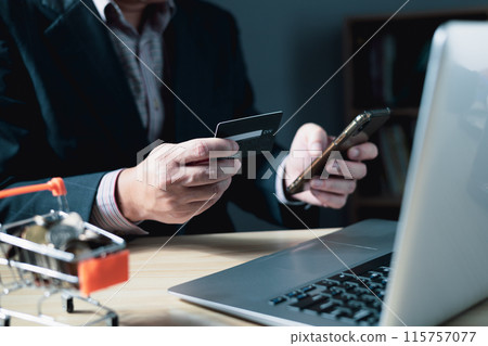 businessman uses a computer laptop and credit card to buy or purchase produce payment online and sits on the chair in the living room at home. The concept of finance and online shopping. businessman uses a computer laptop and credit card to buy or purchase produce payment online and sits on the chair in the living room at home. The concept of finance and online shopping. 115757077
