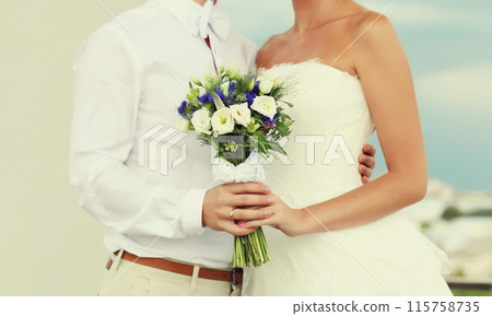 Wedding couple, bride in white dress with bouquet of flowers and groom in shirt holding hands 115758735