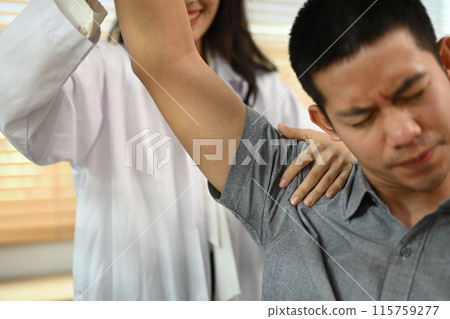 Physical therapist helping male patient doing stretching exercises, shoulder joint treatment 115759277