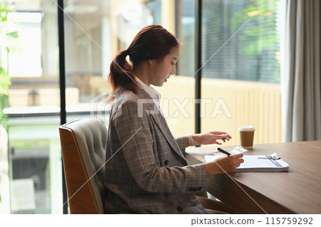 Side view of financial accountant sitting at desk working reviewing financial data or accounting statistics Side view of financial accountant sitting at desk working reviewing financial data or accounting statistics 115759292