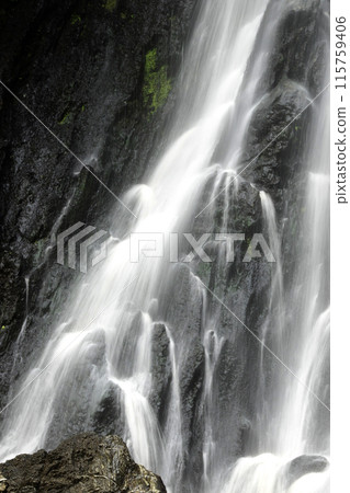 The water flows down from the rock cliff. It hits the cliff and creates mist 115759406