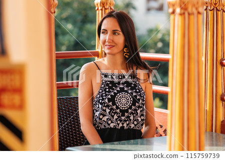 A beautiful woman in an oriental dress is sitting at a table. The concept of luxury living A beautiful woman in an oriental dress is sitting at a table. The concept of luxury living 115759739