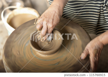 Human hand sculpting a craft from raw clay Human hand sculpting a craft from raw clay 115760915