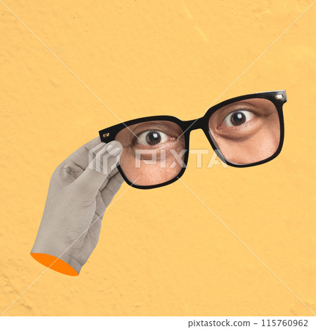 A man is holding a pair of glasses and looking at the camera 115760962