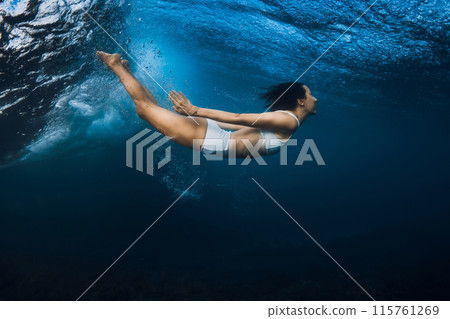 Surfer girl dive under powerful wave in ocean. Surfer girl dive under powerful wave in ocean. 115761269