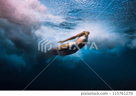 Surf girl dives underwater with ocean wave. Diving under barrel waves without surfboard Surf girl dives underwater with ocean wave. Diving under barrel waves without surfboard 115761270