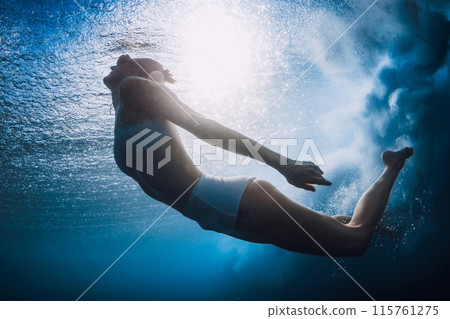 Woman dive without surfboard underwater with ocean wave. Woman dive without surfboard underwater with ocean wave. 115761275