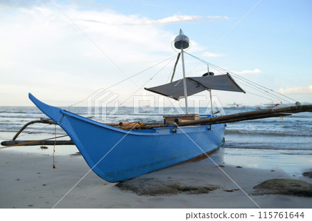 A traditional Filipino fishing boat Bangca in the evening on the seashore sand beach in Sabang, Puerto Princesa, Palawan 115761644