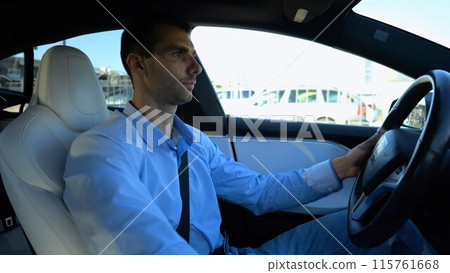 Profile of handsome businessman driving a modern electric car at urban road. Male successful entrepreneur riding on electrical vehicle at city. Young man commuting to work at sunny day. Slow motion 115761668