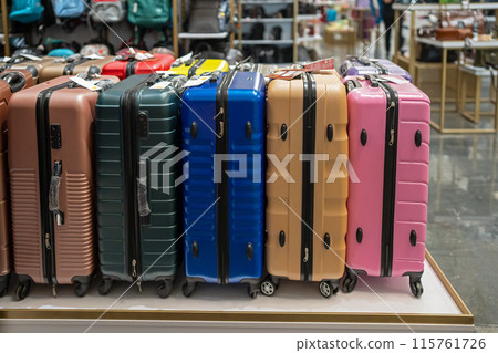 Multi-colored suitcases are sold in a store. A customer chooses a suitcase for luggage in a department store. Tourism. 115761726