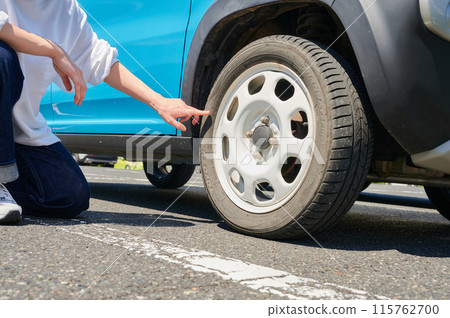 Woman checking car tire flat air pressure 115762700
