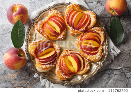 Delicious dessert peach puff heart cake with fresh fruit and jam close-up in a plate. Horizontal top view Delicious dessert peach puff heart cake with fresh fruit and jam close-up in a plate. Horizontal top view 115762793