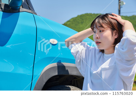 Woman holding her head in front of her car, flat tire, trouble 115763020