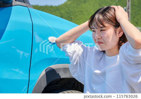 Woman holding her head in front of her car, flat tire, trouble 115763026