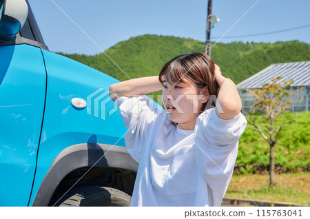 Woman holding her head in front of her car, flat tire, trouble 115763041