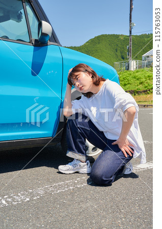Woman holding her head in front of her car, flat tire, trouble 115763053