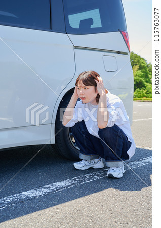 Woman holding her head in front of her car, flat tire, trouble 115763077