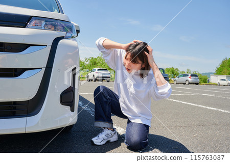 Woman holding her head in front of her car, flat tire, trouble 115763087