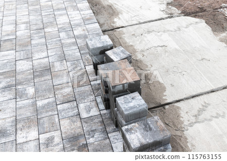 Street paving works in progress. Gray paving slabs lay on the ground Street paving works in progress. Gray paving slabs lay on the ground 115763155