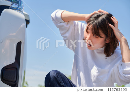 Woman holding her head in front of her car, flat tire, trouble 115763393