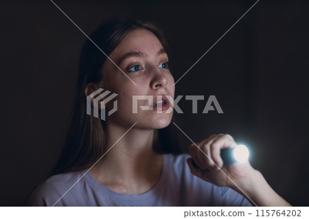 Woman scared holding hand flashlight in darkness and afraid of violence criminal robbery Woman scared holding hand flashlight in darkness and afraid of violence criminal robbery 115764202
