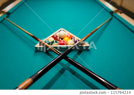 Billiard accessories balls and crossed cues on a billiard table 115764214