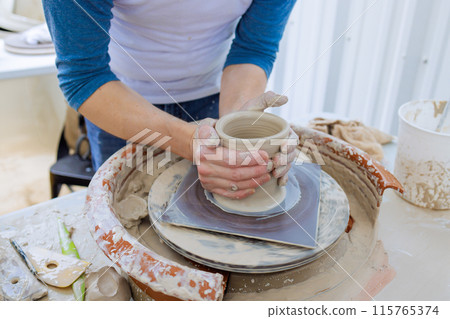 On potter wheel, potter hand sculpts soft clay with wet hands is crafting clay dishes 115765374
