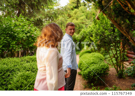 pregnant brunette woman in pink dress holding man's hand and following him. 115767349