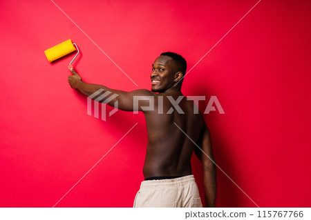 Happy construction worker holding paint roller performing interior renovation with optimism. 115767766