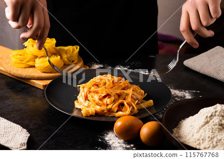 Hand uses chopsticks to pickup tasty noodles. Asian meal on a table, junk food concept Hand uses chopsticks to pickup tasty noodles. Asian meal on a table, junk food concept 115767768