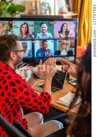 A man and woman are sitting at a table with a computer monitor in front of them 115767883
