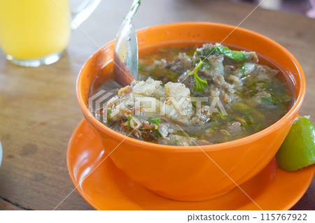 A bowl filled with rib soup on a light wooden table. A bowl filled with rib soup on a light wooden table. 115767922