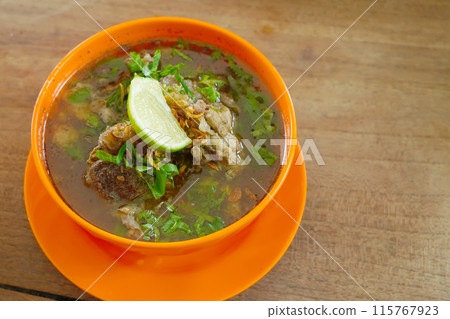 A bowl filled with rib soup on a light wooden table. A bowl filled with rib soup on a light wooden table. 115767923