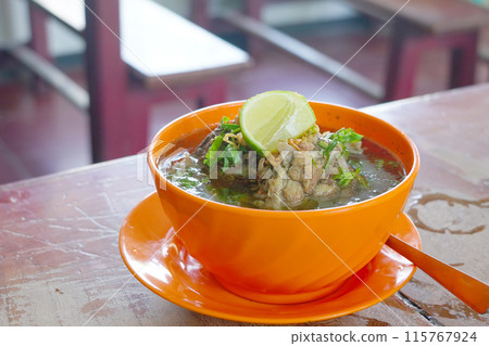 A bowl filled with rib soup on a light wooden table. A bowl filled with rib soup on a light wooden table. 115767924