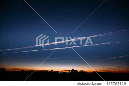 Night Starry Sky And Noctilucent Clouds Above Summer Countryside Landscape. Glowing Stars And Night Shining Clouds 115768129