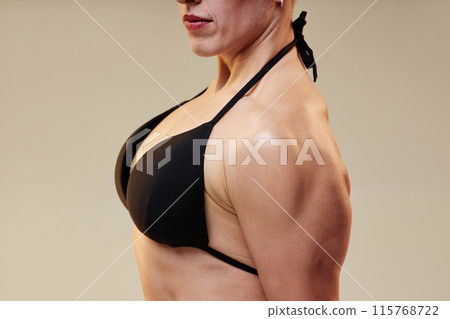 Cropped medium shot of pumped up sportswoman in side triceps pose keeping torso muscles controlled Cropped medium shot of pumped up sportswoman in side triceps pose keeping torso muscles controlled 115768722