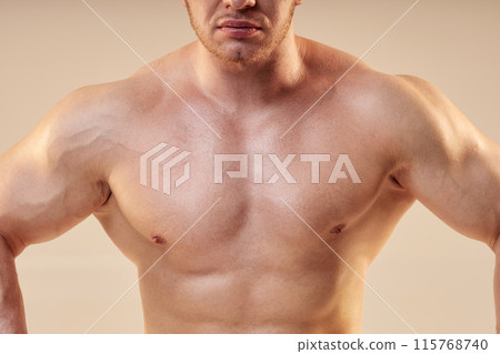 Cropped shot of male bodybuilder giving front lat spread pose. Bare muscular chest of sportsman isolated on neutral background, copy space Cropped shot of male bodybuilder giving front lat spread pose. Bare muscular chest of sportsman isolated on neutral background, copy space 115768740