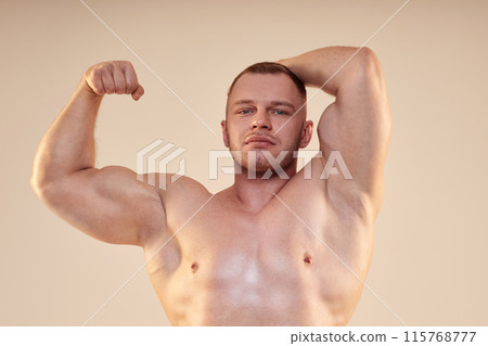 Medium shot of attractive male bodybuilder wearing no shirt in front lat and bicep pose looking at camera isolated over neutral background Medium shot of attractive male bodybuilder wearing no shirt in front lat and bicep pose looking at camera isolated over neutral background 115768777
