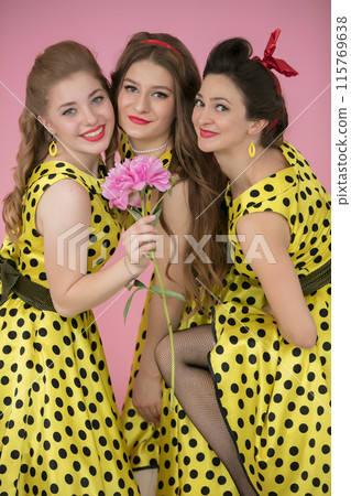 Retro girls. Three beautiful women in yellow dresses with polka dots. 115769638