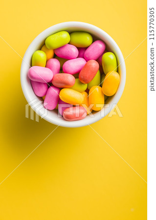 Colorful hard mint Candies in bowl on yellow background. Top view. Colorful hard mint Candies in bowl on yellow background. Top view. 115770305