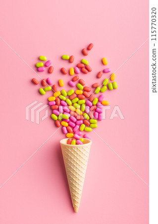 Colorful hard mint Candies in ice cream cone on pink background. Top view. Colorful hard mint Candies in ice cream cone on pink background. Top view. 115770320