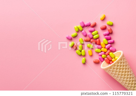 Colorful hard mint Candies in ice cream cone on pink background. Top view. Colorful hard mint Candies in ice cream cone on pink background. Top view. 115770321