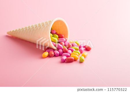 Colorful hard mint Candies in ice cream cone on pink background. Colorful hard mint Candies in ice cream cone on pink background. 115770322